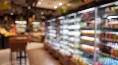 Defocused Image Of Food And Drink On Shelves In Illuminated Store