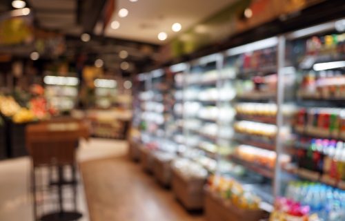 Defocused Image Of Food And Drink On Shelves In Illuminated Store