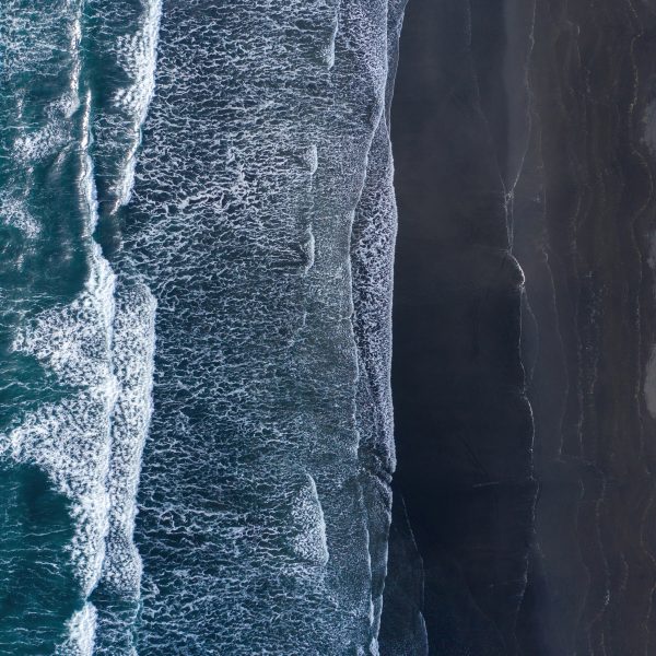 Aerial view of Atlantic ocean waves washing black sandy beach