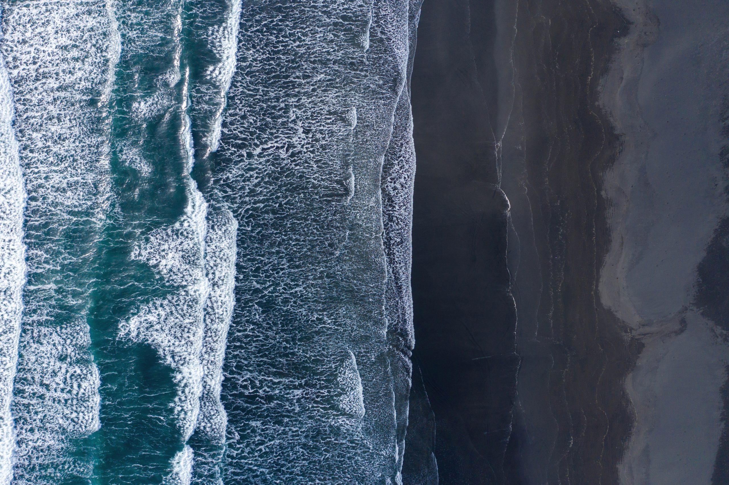 Aerial view of Atlantic ocean waves washing black sandy beach