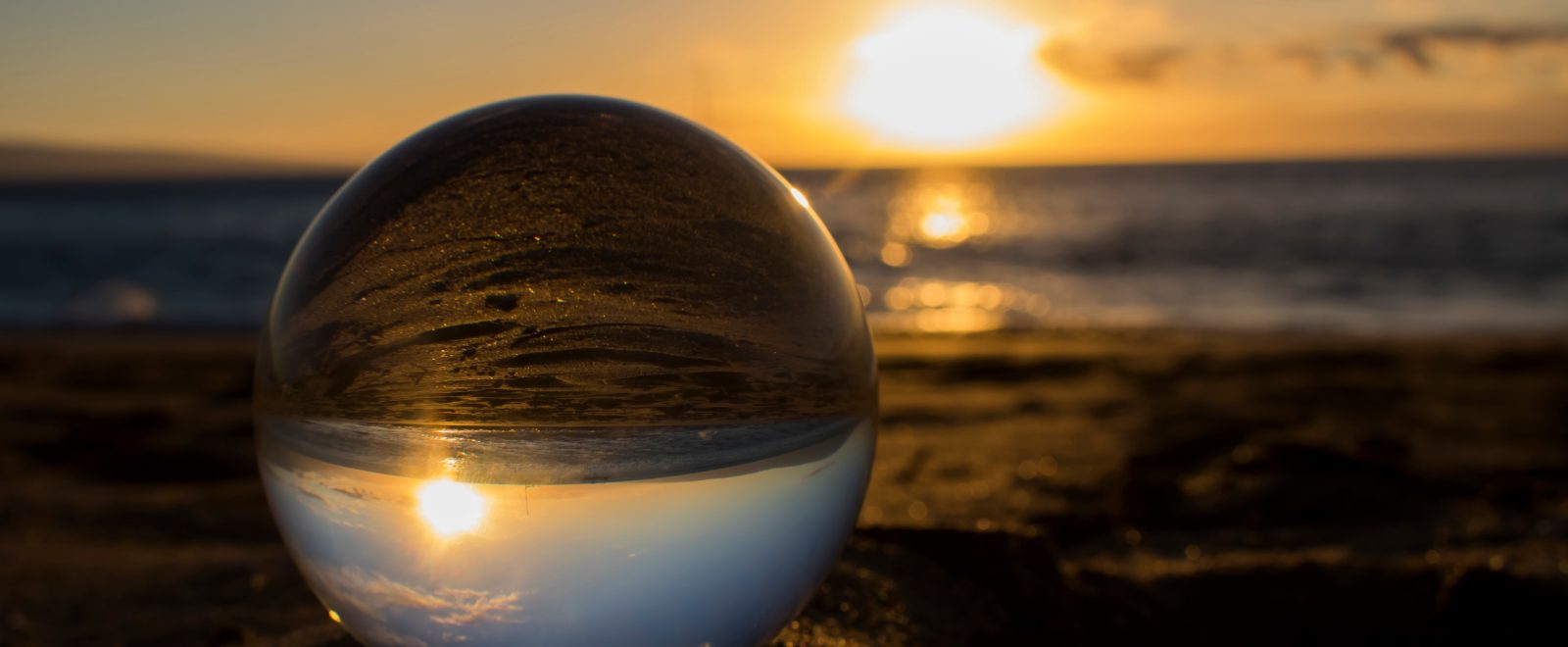 Sunset on Sand Through Glass Ball with Ocean