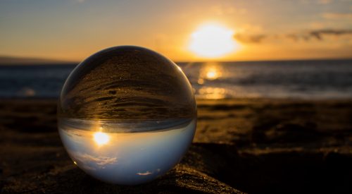Sunset on Sand Through Glass Ball with Ocean