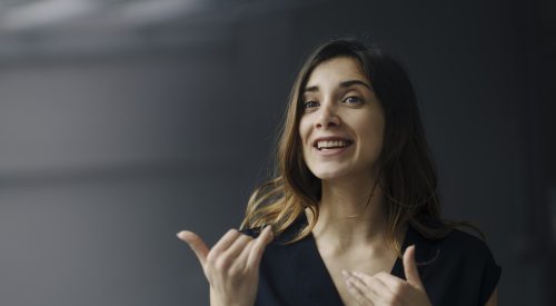 Portrait of gesturing young businesswoman against grey background