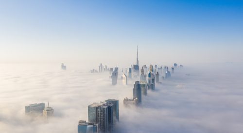 Aerial view of Dubai frame and skyline covered in dense fog during winter season