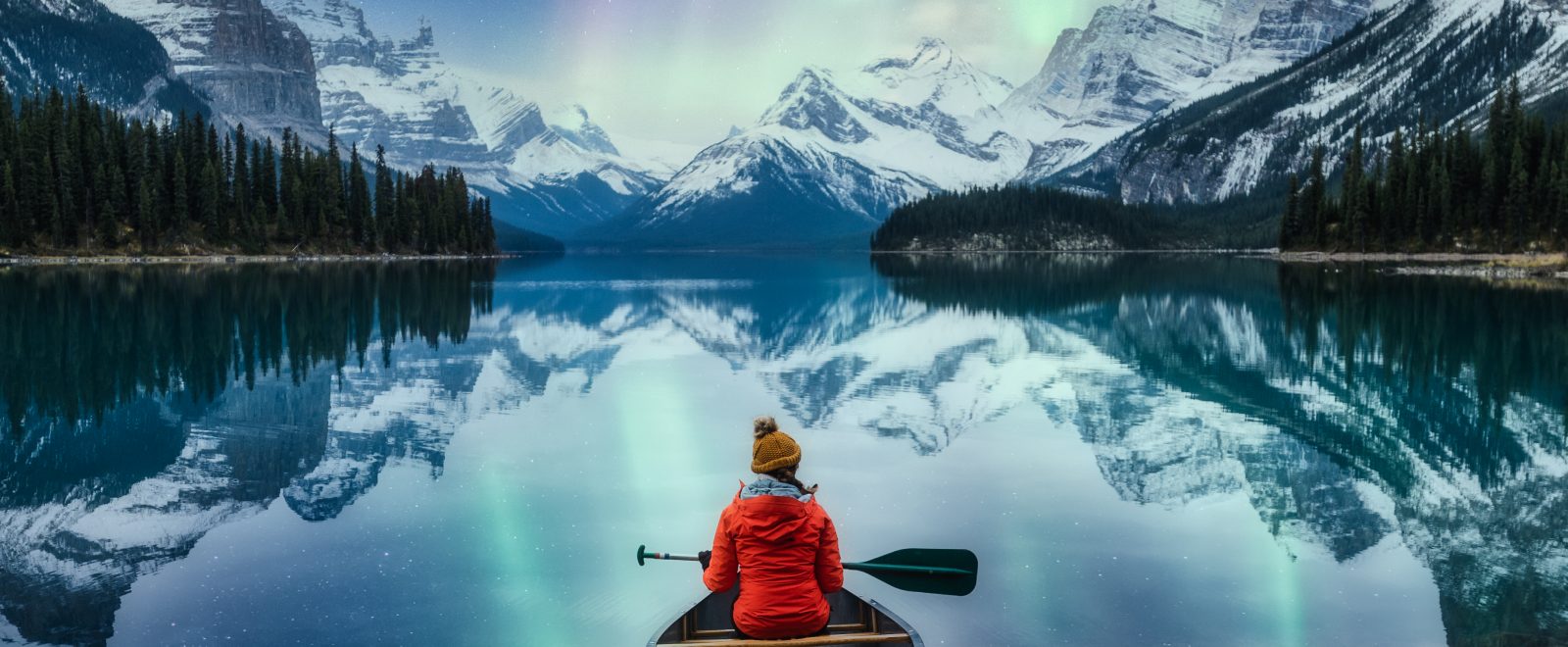 Beautiful aurora borealis over spirit island with female traveler on canoe at Jasper national park