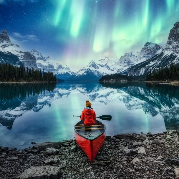 Beautiful aurora borealis over spirit island with female traveler on canoe at Jasper national park
