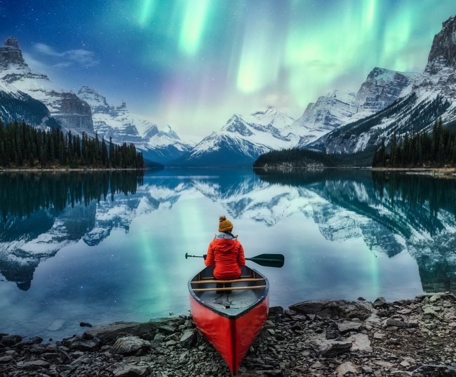 Beautiful aurora borealis over spirit island with female traveler on canoe at Jasper national park