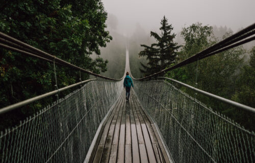 Lady walking over a rope and wood bridge in stormy weather