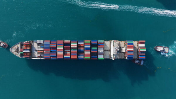 Aerial view of a cargo ship entering the busy port of Miami near South Pointe Pier at sunset