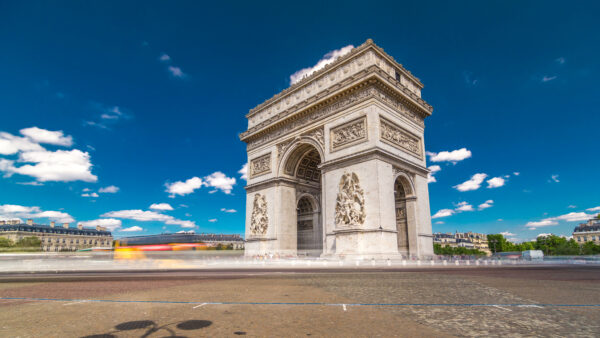 The Arc de Triomphe (Triumphal Arch of the Star) timelapse hyperlapse with traffic on a circle road. Famous monument in Paris, standing at the western end of the Champs-Elyseees. Blue sky at summer