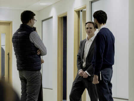 Three men standing, in conversation