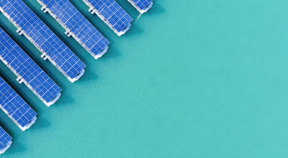 A top-down photo of floating solar panels on turquoise water