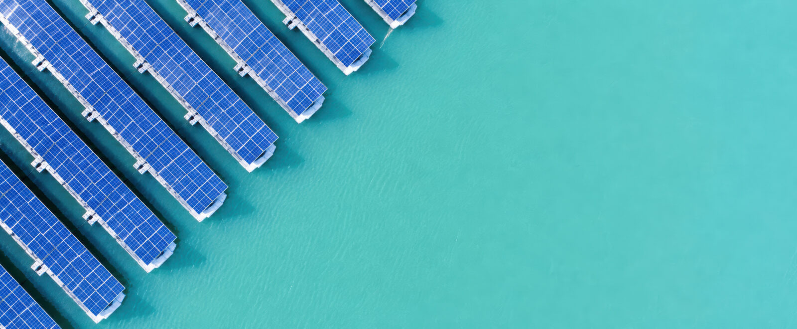 A top-down photo of floating solar panels on turquoise water