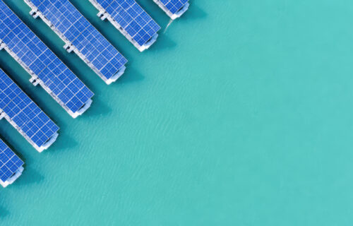 A top-down photo of floating solar panels on turquoise water